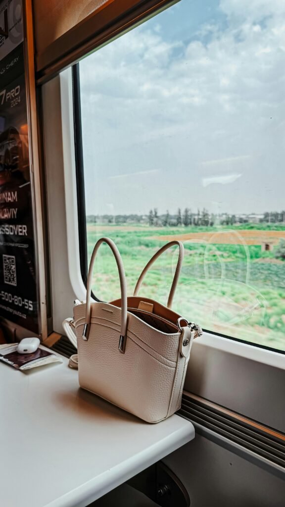 A peaceful train ride in Uzbekistan with a scenic view of lush fields through a window.
